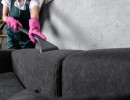 woman in rubber gloves cleaning sofa with vacuum cleaner1054