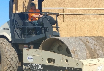 worker driving a commerial ground packer