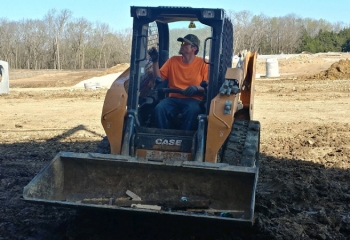 worker driving a front end loader tractor