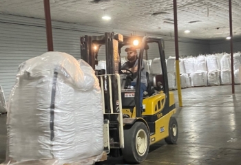 Man driving a warehouse loader carrying a large pallet.