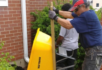 Men working on landscaping the outside of a building.